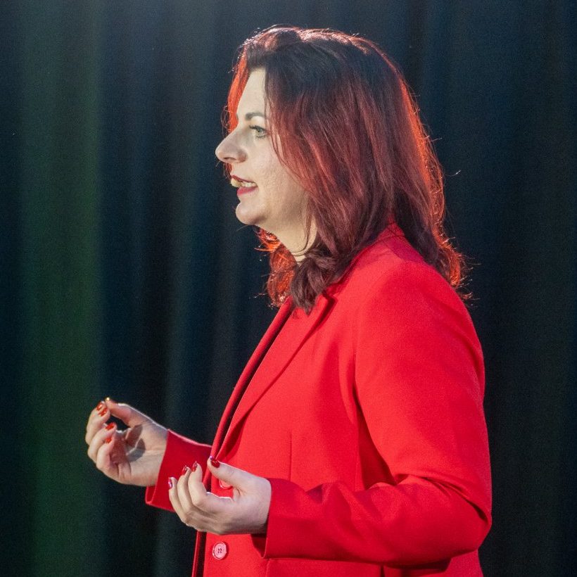 Mandy Henze bei einem Vortrag im roten Blazer
